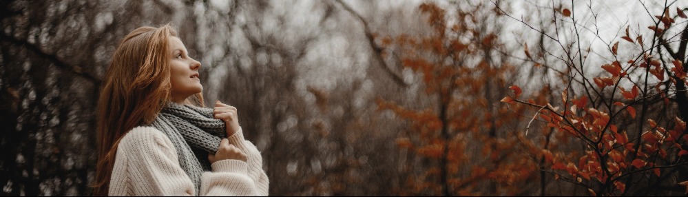 Ragazza nel bosco invernale che osserva gli alberi